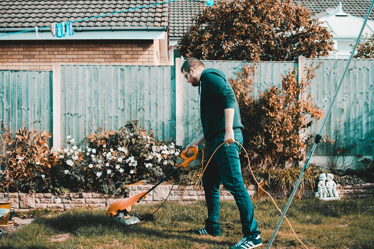 hero-img-02 A man using an electric mower in a garden on a sunny day, capturing outdoor chores and gardening vibes.
