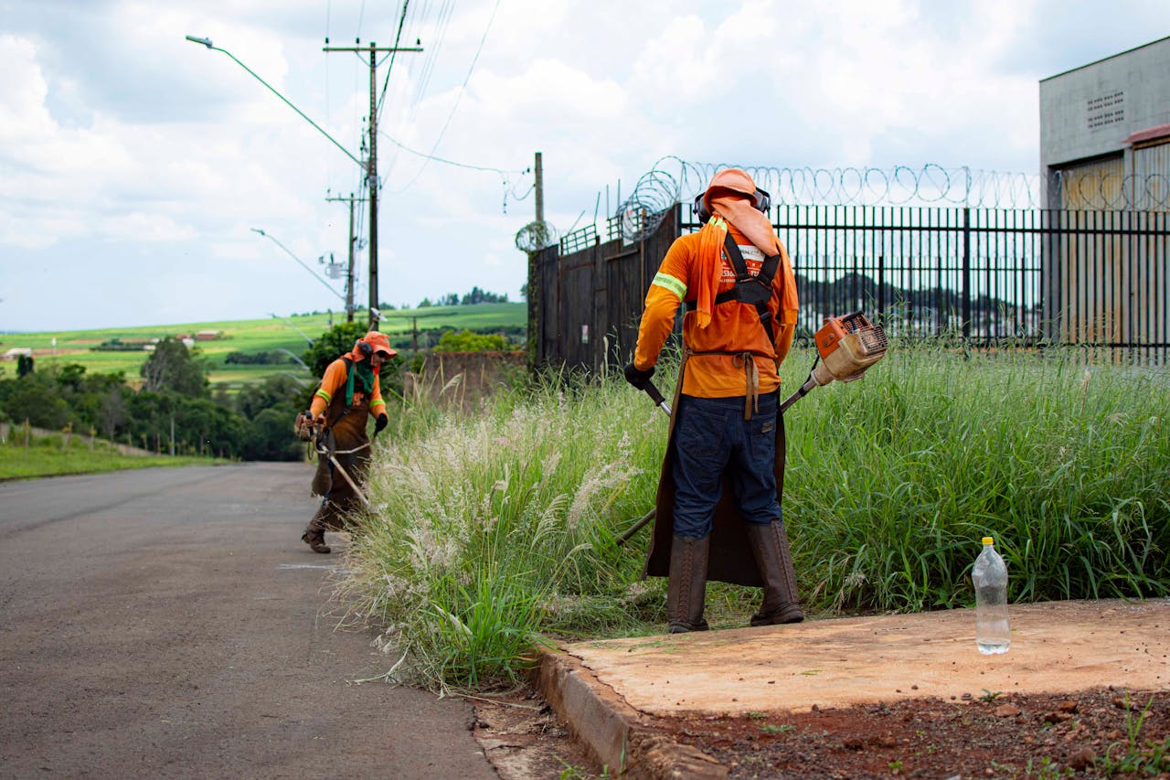 services-03 Two workers in Londrina, Brazil, trimming roadside grass with weed whackers.